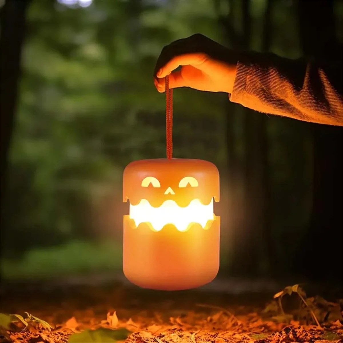 SpookLampion aan het koord in de hand, het licht schijnt uit de mond van de pompoen