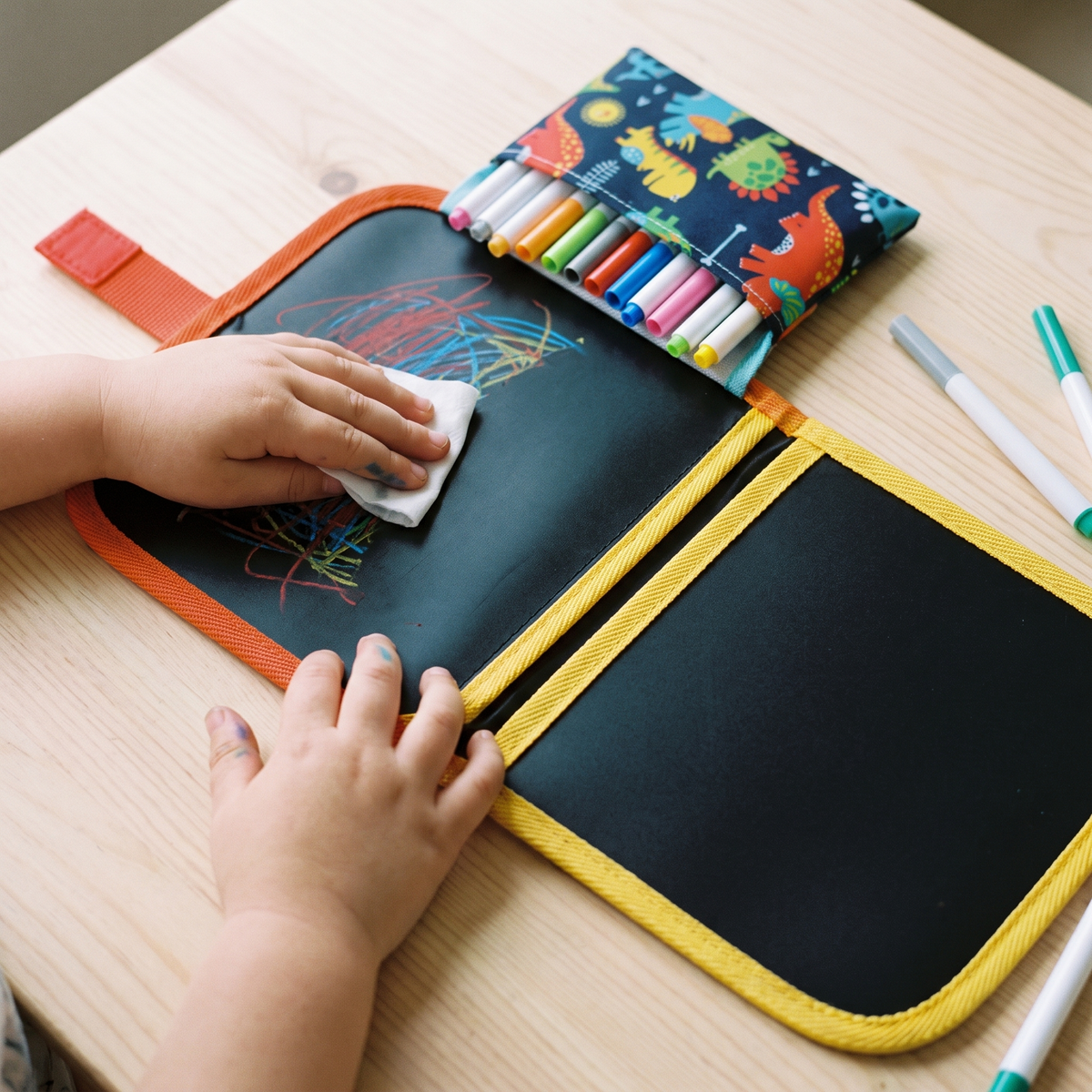 Kinderhand veegt een tekening van de zwarte pagina van het KrabbelBoek
